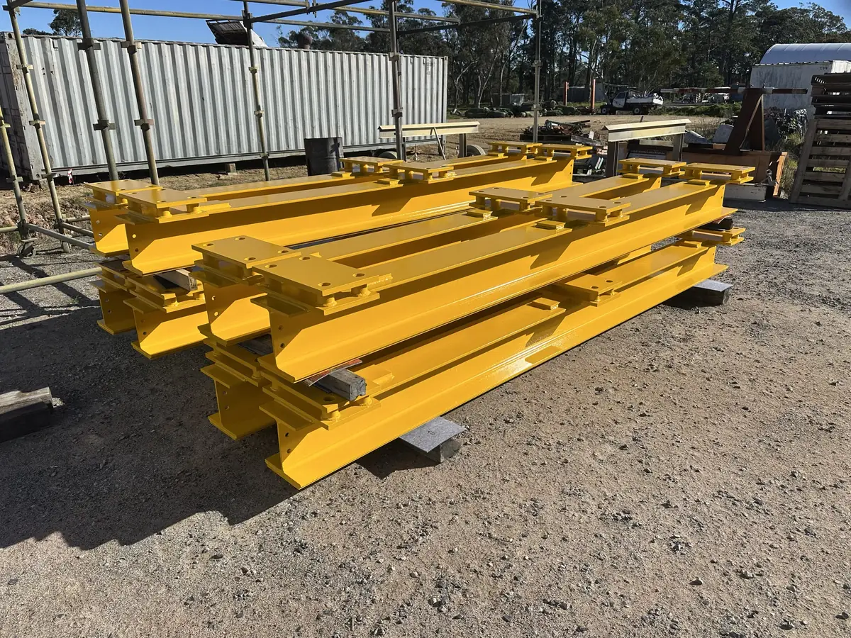 Fabricated structural steel beams with base plates, sandblasted and painted gloss yellow